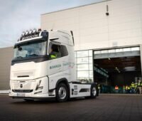 Enercons erster E-LKW für die Transportlogistik in Fahrt vor einer Gewerbehalle.