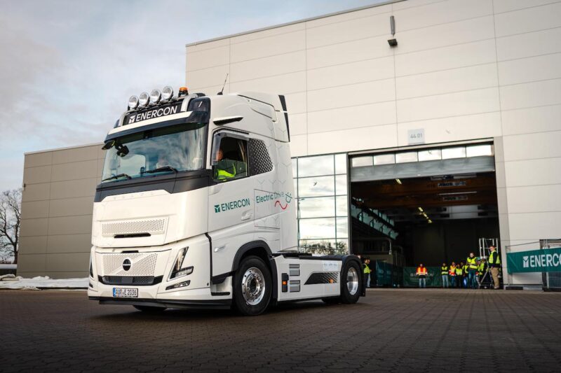 Enercons erster E-LKW für die Transportlogistik in Fahrt vor einer Gewerbehalle.