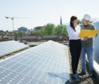 Eine Frau und ein Mann führen eine Besprechung durch auf einem DSach mit PV-Anlage.