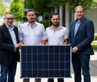 Vier Personen halten gemeinsam ein Solarmodul.