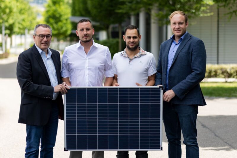Vier Personen halten gemeinsam ein Solarmodul.