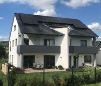 Einfamiliemhaus freistehend mit PV-Anlage auf dem Dach und Garten.