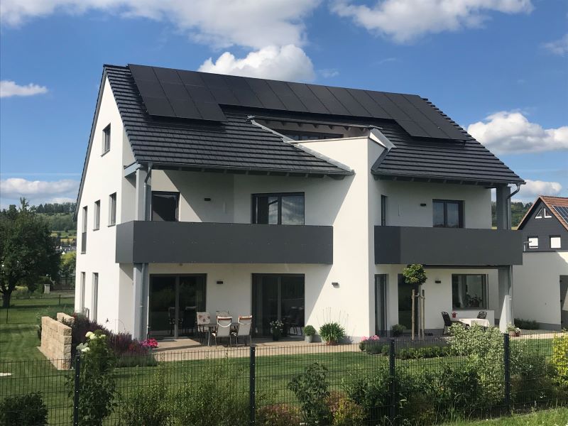 Einfamiliemhaus freistehend mit PV-Anlage auf dem Dach und Garten.