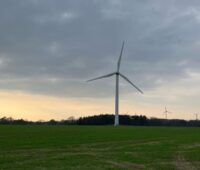 Windpark im Flachland vor Horizont mit Wolken und Farbenspiel am Himmel.
