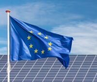 Im Bild eine Europaflagge vor Photovoltaik-Anlage als Symbol für die Europäische Solarakademie.