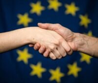 Handeschütteln vor einer Fahne der EU
