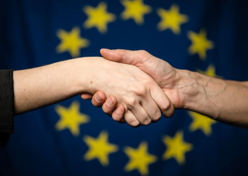 Handeschütteln vor einer Fahne der EU
