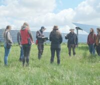 Zu sehen ist eine Gruppe von Student*innen des Projekts EULE inmitten einer Photovoltaik-Freiflächenanlage.
