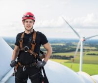 Zu sehen ist eine Techniker auf einer Windenergieranlage. EWE und Enercon legen ihren Bestand an Windparks zusammen.