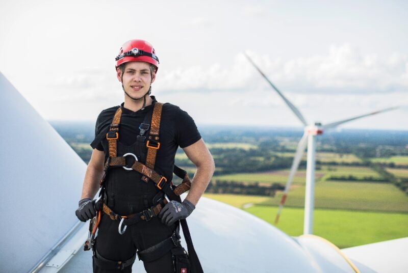 Zu sehen ist eine Techniker auf einer Windenergieranlage. EWE und Enercon legen ihren Bestand an Windparks zusammen.