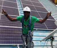 Im Bild ein People of Color, der eine Photovoltaik-Anlage installiert als Symbol für Photovoltaik Impact Investments in Afrika.