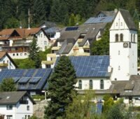 Zu sehen ist das „Schönauer Schöpfungsfenster“. Es handelt sich um zwei Ü20-Photovoltaik-Anlagen auf den Dächern der Kirche und des Gemeindehauses in Schönau.