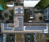 Blick auf das Dach eines Wohnblocks mit Photovoltaik aus der Vogelperspektive