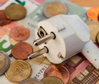 Ein Stromstecker und Geld als Symbol für die Kosten der Energiewende.