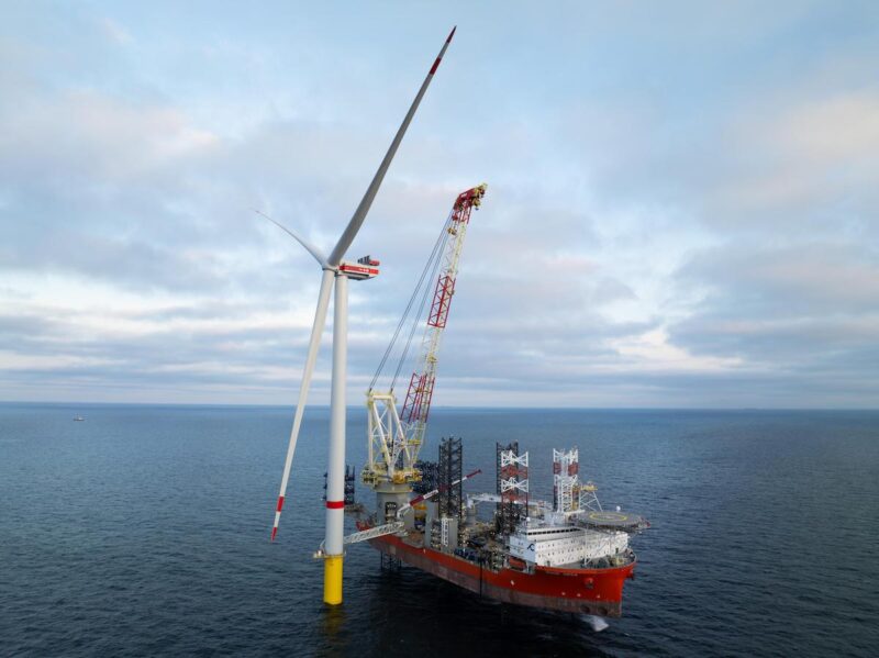 Ein Schiff liegt neben einer Offshore-Windkraftanlage