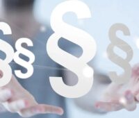 Das Bild zeigt zwei offene, nach vorn Gestreckte Hände über denen Paragrafen-Zeichen schweben als Symbol für die Kritik zum Referentenentwurf EEG und Netzpaket.