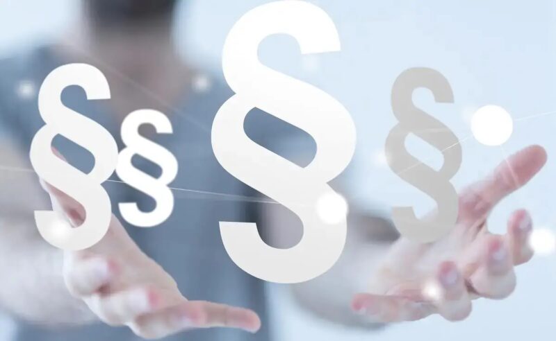 Das Bild zeigt zwei offene, nach vorn Gestreckte Hände über denen Paragrafen-Zeichen schweben als Symbol für die Kritik zum Referentenentwurf EEG und Netzpaket.