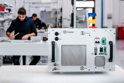 Serienfertigung mit einem Elektrolyseur auf einem Arbeitstisch udn tätige Mitarbeiter im Hintergrund.