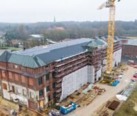 Das historische Gebäude der Bremer Wollkämmerei in Bremen-Nord mit Baukran, die Wärmeversorgung erfolgt über ein neues Wärmenetz.