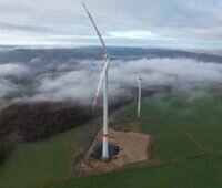 Mehrere Windturbinen im wolkigen deutschen Mittelgebirge.