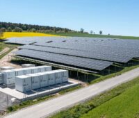 Rapsfeld neben einer PV-Anlage sowie Batteriespeichern.