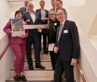 Gruppenfoto mit acht Menschen auf neuer Treppe - Einweihung am neuen Forschungszentrum für Batterie- und Leistungselektronik