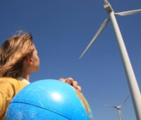 Ein Kind mit einer Weltkugel neben Windkraftanlagen, als Symbol für Energieerzeugung, erneuerbare Energien, Kohleausstieg