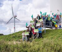 Menschengruppe am Fuß einer Windenergieanlage - Symbolbild für Bürgerenergie und Energy Sharing