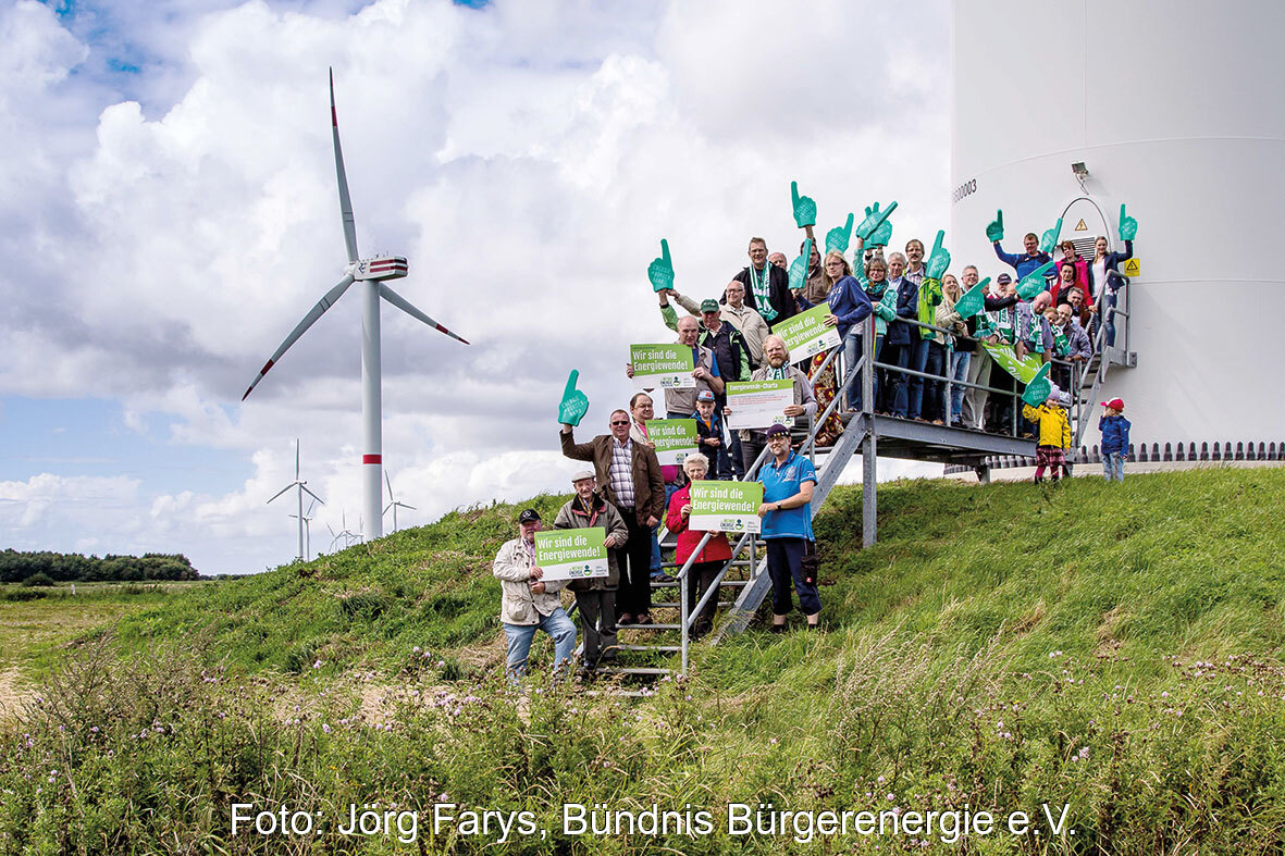 Menschengruppe am Fuß einer Windenergieanlage - Symbolbild für Bürgerenergie und Energy Sharing