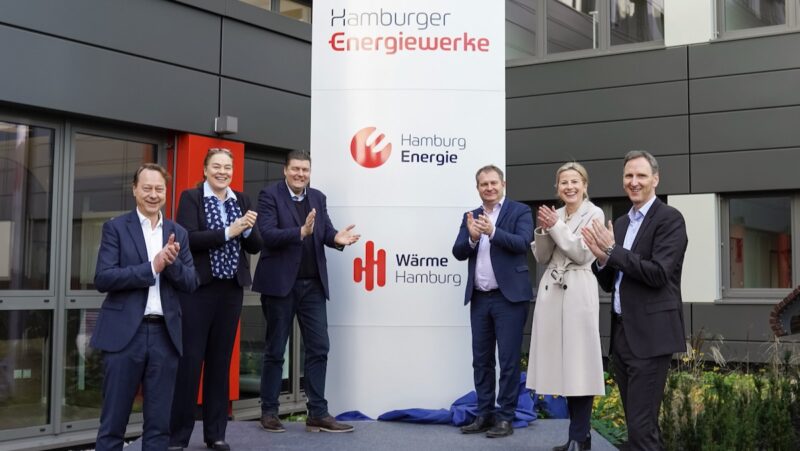 Vier Männer und zwei Frauen stehen neben einem Firmenschild und klatschen in die Hände - es gibt wieder einen städtischen integrierten Energieversorger in Hamburg.