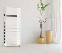 Ein weißer hochkanter Kasten aus mehreren Elementen neben einer Zimmerpflanze - Batteriespeicher Energy-Butler von M-Tec