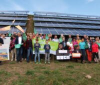 Gruppenfoto einer Bürgerenergiegesellschaft von Modulreihen eines Fotovoltaik-Solarparks