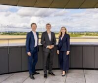 Der Vorstand der Enertrag, bestehende aus Simon Hagedorn, Gunar Hering, Anne Bendzulla vor einem Windpark.