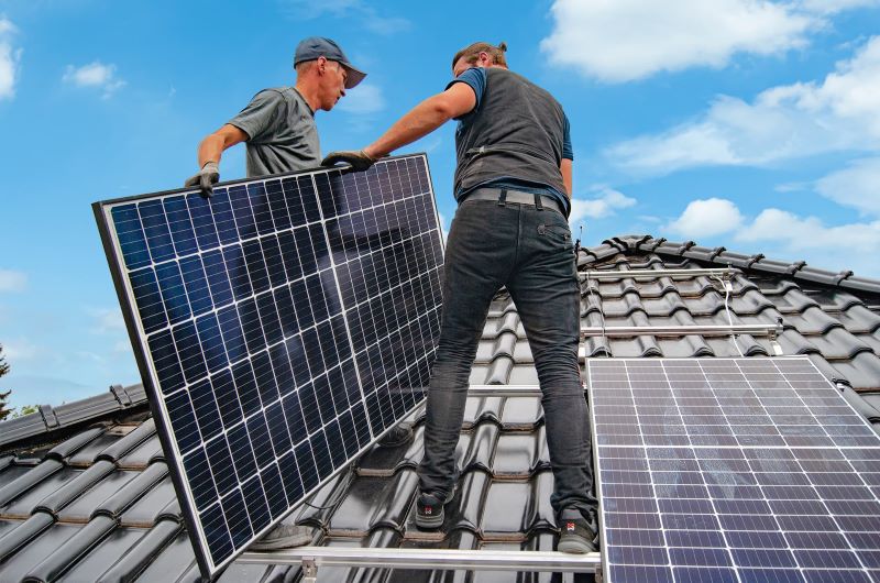 Zwei Enpal-Installateure mit Solarmodulen auf dem Dach.