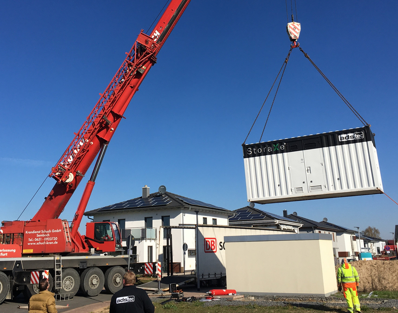 Ein Kran hebt einen Speichercontainer für eine Neubausiedlung.