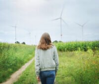 Eine Frau geht auf einem Feldweg auf einen Windpark zu - Symbol für regionalen Ökostrom von E.on