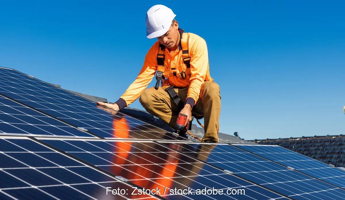 Ein Installateur auf mit Dach schraubt Solarmodule, Eon hat Umfrage zur Photovoltaik durchgeführt.