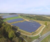 Aus der Vogelperspektive ist ein großer Solarpark zu sehen. Am Rand verläuft eine Autobahn.