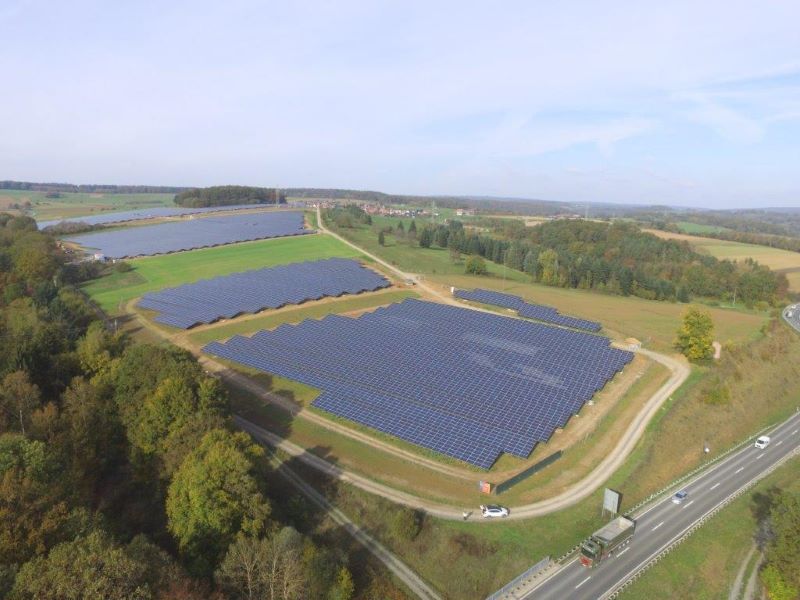 Aus der Vogelperspektive ist ein großer Solarpark zu sehen. Am Rand verläuft eine Autobahn.