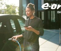 Zu sehen ist eine Frau beim Laden eines E-Autos. Das Eon Analyse-Tool OMNe kann nun Photovoltaik für betriebliche E-Auto-Ladestationen berechnen.