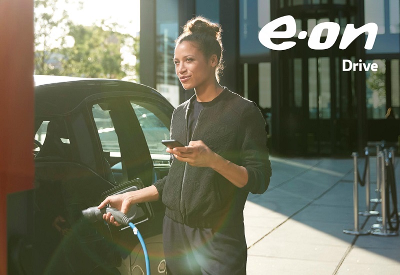Zu sehen ist eine Frau beim Laden eines E-Autos. Das Eon Analyse-Tool OMNe kann nun Photovoltaik für betriebliche E-Auto-Ladestationen berechnen.