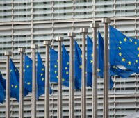 Reihe von wehenden Europaflaggen vor dem Hauptgebäude der EU-Kommission in Brüssel.