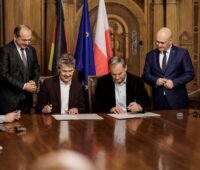 Mehrere Personen bei feierlicher Vertragsunterzeichnung im historischen Ambiente.