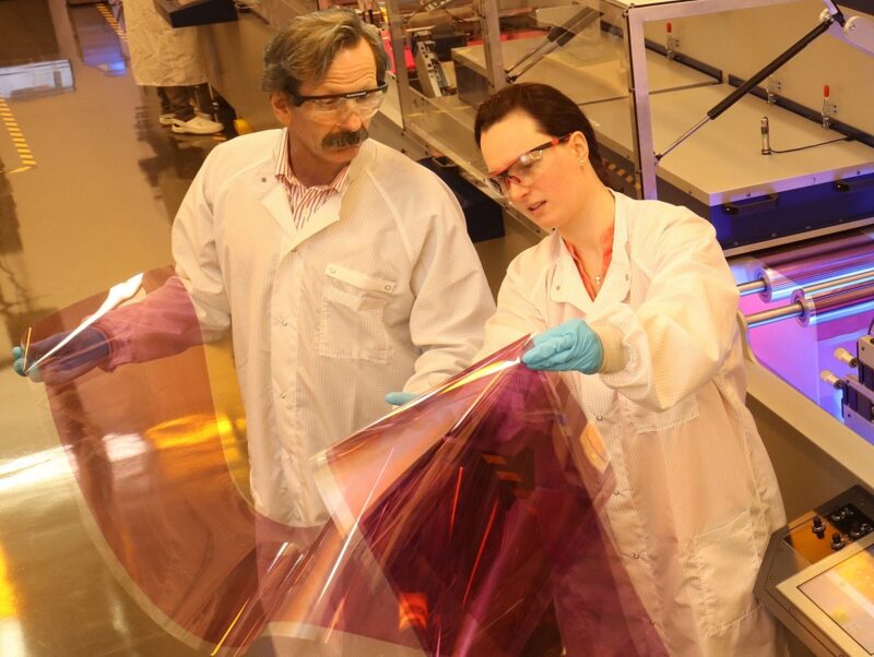 Im Bild sind zwei Wissenschaftler:innen, die Solarzellen aus dem Drucker in den Händen halten, die für Multi-Benefit-PV geeignet sind.