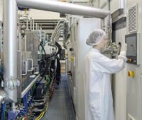 Forscher*in mit Schutzhaube im Labor