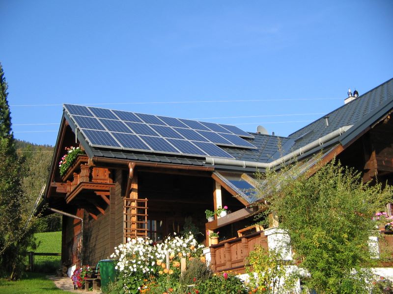 Auf einem Bauernhaus ist eine PV-Anlage installiert. Im Vordergrund sind Blumen gepflanzt.