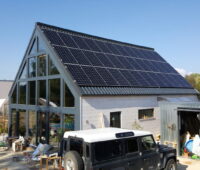 Haus mit Spitzdach, das eine PV-Anlage enthält, die auch Wärme produziert.