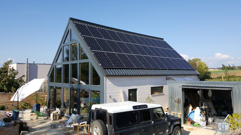 Haus mit Spitzdach, das eine PV-Anlage enthält, die auch Wärme produziert.