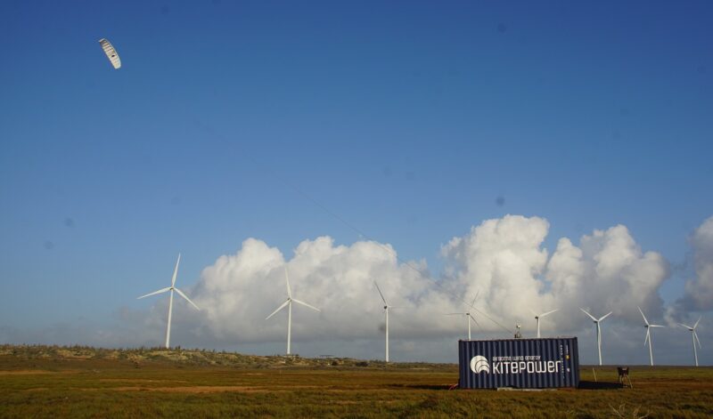 Ein Drachen fliegt vor Windenergieanlagen, Kitepower testet sein Flugwindkraft-System in Irland.