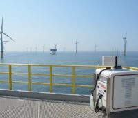 Zu sehen ist ein Lasergerät mitten im Offshore-Windpark, mit dessen Hilfe die Leistung von Offshore-Windparks exakter vorhersehbar werden soll.